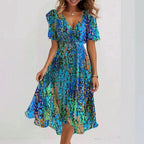 Femme de dos portant la robe midi verte à fleurs, ourlet asymétrique visible